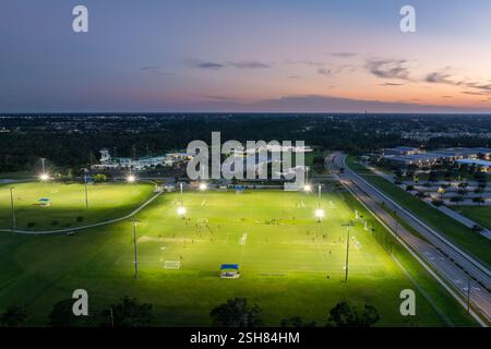 Persone che giocano a calcio in uno stadio pubblico illuminato al tramonto. Concetto di stile di vita attivo Foto Stock