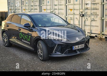 Auto elettrica nera in un parcheggio di fronte ai container, Deer e- Carsharing Vehicle MG4, Calw District, Germania, Europa Foto Stock