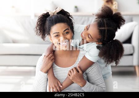 Bella madre nera e figlia coccolare mentre si esercita Foto Stock
