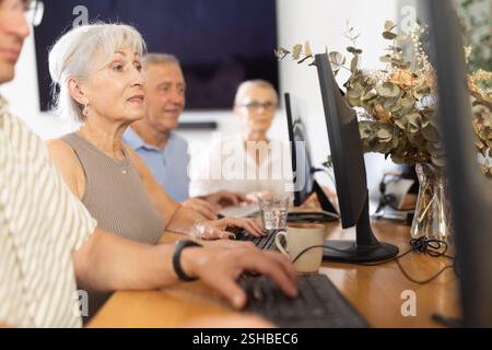 Anziana che impara programmi informatici in sala di formazione Foto Stock