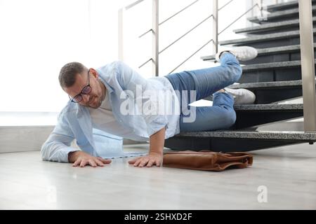 Uomo ferito sulle scale dell'edificio dopo la caduta. Incidente pericoloso Foto Stock