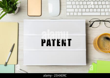 Licenza. Scatola luminosa con brevetto Word, tastiera per computer e cancelleria su tavolo in legno, piano Foto Stock