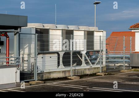 Una grande unità di raffreddamento è situata sul tetto di un edificio, protetta dalle recinzioni circostanti. La struttura è progettata per la ventilazione e l'aria condizionata Foto Stock
