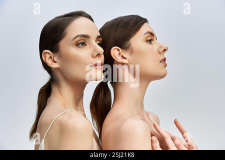 Due bellissime sorelle gemelle si mettono in posa uno dietro l'altro, mettendo in risalto le loro caratteristiche eleganti e il loro legame. Foto Stock