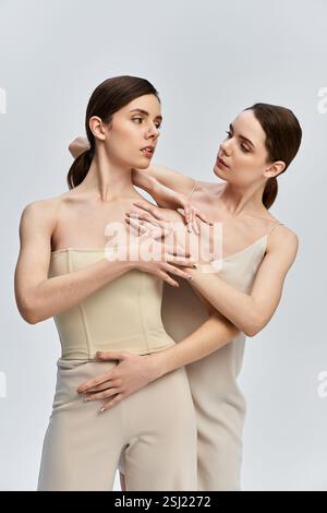 Due bellissime gemelle si collegano attraverso pose artistiche in un'atmosfera morbida e accattivante. Foto Stock