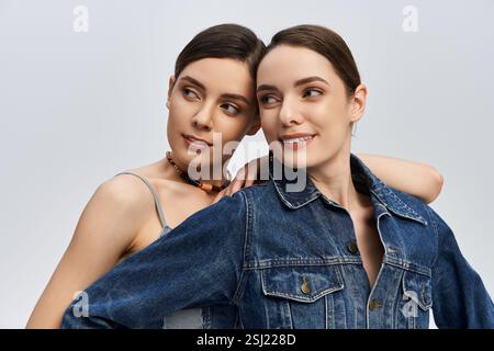 Due belle sorelle si abbracciano, sorridono e si godono il tempo mentre si vestono. Foto Stock