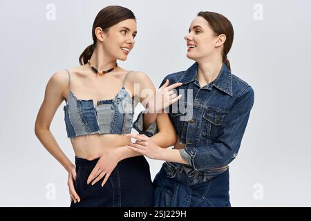 I gemelli mostrano la loro personalità vibrante in denim chic su uno sfondo morbido. Foto Stock