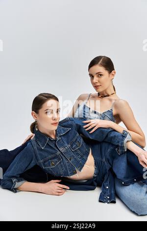 Due bellissime sorelle si sposano graziosamente in abiti di tendenza in denim, trasudando eleganza e stile. Foto Stock