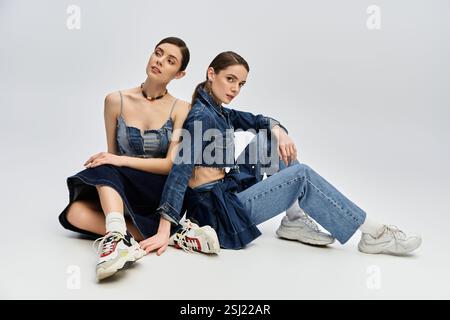 Due eleganti outfit da donna in denim e sneaker moderne in uno studio luminoso. Foto Stock