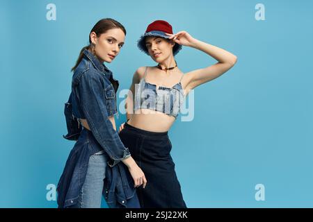 Due eleganti gemelle mostrano con fiducia la loro personalità vibrante in denim alla moda. Foto Stock