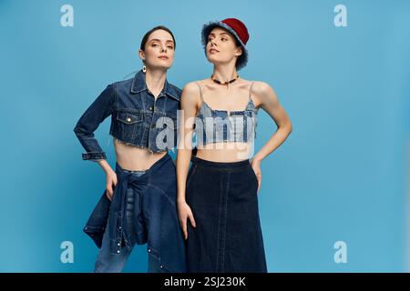 Due bellissime gemelle si mettono in posa con fiducia, indossando gli eleganti abiti in denim. Foto Stock