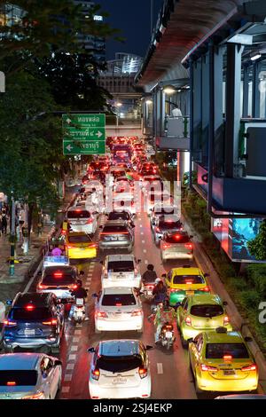 Una vivace scena notturna su Sukhumvit Road a Bangkok cattura l'essenza della vita urbana con il traffico intenso. L'immagine mostra un mare di tai rosso Foto Stock