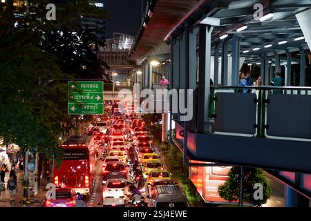 Una vivace scena notturna su Sukhumvit Road a Bangkok cattura l'essenza della vita urbana con il traffico intenso. L'immagine mostra un mare di tai rosso Foto Stock