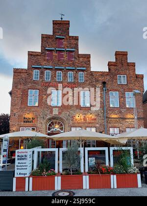 Edificio storico in mattoni a Travemünde, Germania, con gradini e una vivace caffetteria al piano terra. Foto Stock