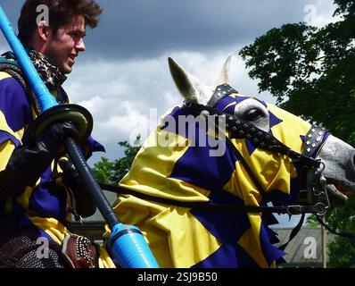 Rievocatore storico, uomo vestito da cavaliere di mezza età a cavallo, con lancia in mano, cavallo che indossa abiti decorati con caparison (trapper), giostra Foto Stock