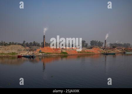 Il fumo spensierato sorge dai forni di mattoni lungo le rive del fiume Shitalakshya a Rupganj, Narayanganj, Bangladesh, inquinando l'aria e oscurando il Foto Stock