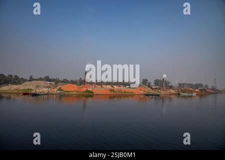 Il fumo spensierato sorge dai forni di mattoni lungo le rive del fiume Shitalakshya a Rupganj, Narayanganj, Bangladesh, inquinando l'aria e oscurando il Foto Stock