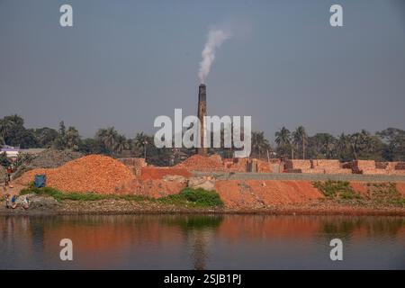 Il fumo spensierato sorge dai forni di mattoni lungo le rive del fiume Shitalakshya a Rupganj, Narayanganj, Bangladesh, inquinando l'aria e oscurando il Foto Stock