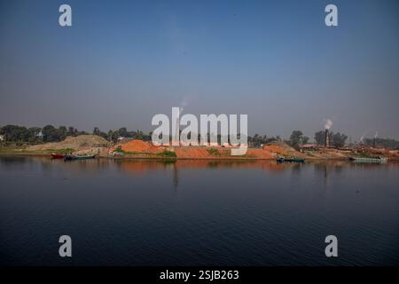 Il fumo spensierato sorge dai forni di mattoni lungo le rive del fiume Shitalakshya a Rupganj, Narayanganj, Bangladesh, inquinando l'aria e oscurando il Foto Stock