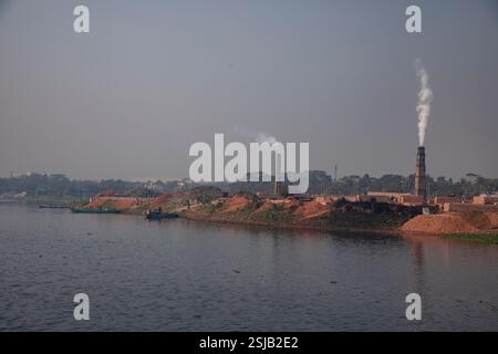 Il fumo spensierato sorge dai forni di mattoni lungo le rive del fiume Shitalakshya a Rupganj, Narayanganj, Bangladesh, inquinando l'aria e oscurando il Foto Stock