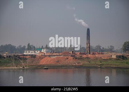 Il fumo spensierato sorge dai forni di mattoni lungo le rive del fiume Shitalakshya a Rupganj, Narayanganj, Bangladesh, inquinando l'aria e oscurando il Foto Stock