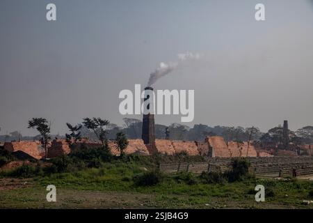 Il fumo spensierato sorge dai forni di mattoni lungo le rive del fiume Shitalakshya a Rupganj, Narayanganj, Bangladesh, inquinando l'aria e oscurando il Foto Stock