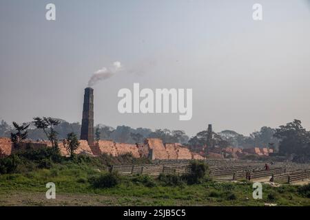 Il fumo spensierato sorge dai forni di mattoni lungo le rive del fiume Shitalakshya a Rupganj, Narayanganj, Bangladesh, inquinando l'aria e oscurando il Foto Stock