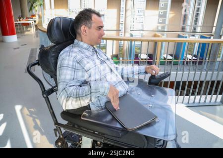 Uomo in sedia a rotelle in ufficio Foto Stock