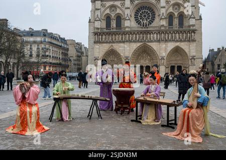 Musicisti cinesi vestiti tradizionalmente che suonano strumenti d'epoca di fronte alla cattedrale di Notre Dame sulla facciata occidentale, girati per la TV cinese. Parigi Foto Stock