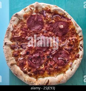 Una deliziosa pizza al peperoni con crosta dorata e formaggio fuso, perfetta per tutti gli amanti della pizza Foto Stock