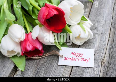 Tulipani con tag e testo per la festa della mamma su sfondo in legno Foto Stock