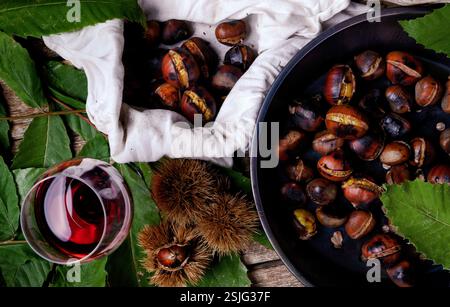 Vista dall'alto di castagne arrostite in padella di ferro sul tavolo di legno. Foto Stock