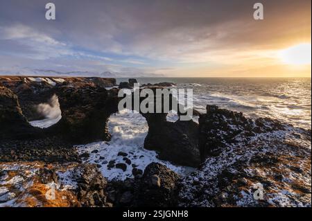 Vista dell'arco roccioso di Gatklettur all'alba in inverno. Arnarstapi, Hellnar, Penisola di Snaefellsnes, Islanda, Nord Europa. Foto Stock