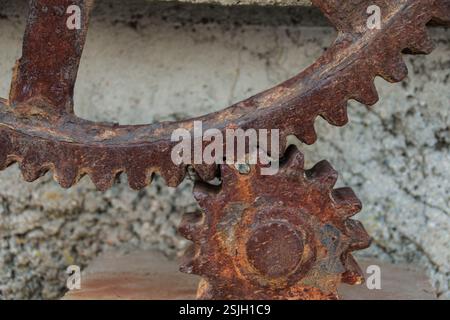 Un ingranaggio grande arrugginito e un ingranaggio piccolo si innestano insieme per azionare un vecchio pezzo di macchinari. Primo piano dei denti. Foto Stock