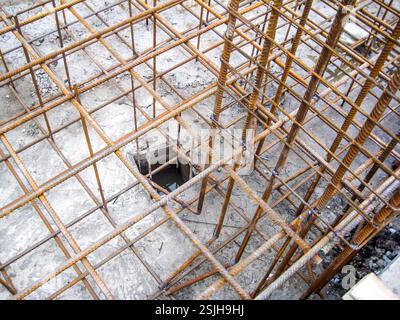 Primo piano di una struttura di armature distesa a terra, pronta per essere racchiusa in calcestruzzo per una fondazione, che mostra un'infrastruttura in sottocostruzione. Foto Stock