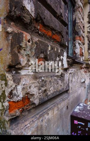 Frammento di un muro distrutto in una vecchia casa di proprietà storica nel quartiere Praga di Varsavia. Primo piano di gesso cadente. Foto Stock