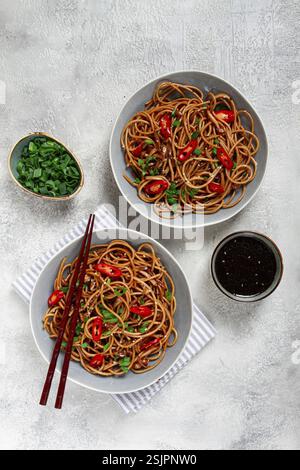 Tagliatelle di Udon, con funghi shimeji, verdure, in salsa, con semi di sesamo, cipolle verdi, cibo vegetariano asiatico, orizzontale, senza persone Foto Stock