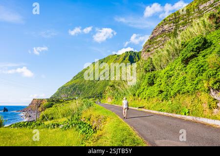Giovane turista che cammina lungo l'oceano nel villaggio di Faja grande, isola di Flores, Azzorre, Portogallo Foto Stock