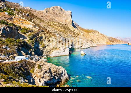 Piccola cappella greca bianca sulla scogliera sul mare presso la spiaggia di Agia Anna, l'isola di Naxos, le Cicladi, Grecia Foto Stock
