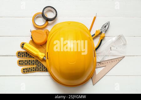 Utensili da falegname e elmetto su sfondo di legno bianco Foto Stock