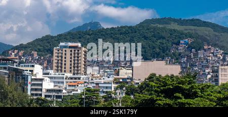 Vista dall'Arpoador Rock degli edifici residenziali di media e alta classe di Ipanema accanto a Cantagalo–Pavao–Pavaozinho, un'area slum composta da due favelas nella zona sud di Rio de Janeiro, situata tra i quartieri di Ipanema e Copacabana - statua del Cristo Redentore sullo sfondo. Foto Stock