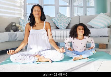 Madre, bambino e esercizio di yoga a casa, si uniscono e fitness mattutino per la consapevolezza. Lotus, mamma e figlia in salotto per la meditazione Foto Stock