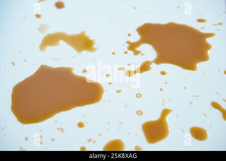 Le macchie di caffè su una superficie bianca creano un motivo astratto Foto Stock