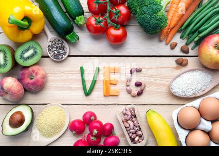 Sano pranzo vegano con avocado, uova, verdura, frutta, riso, semi su sfondo in legno. Viste dall'alto. Foto Stock
