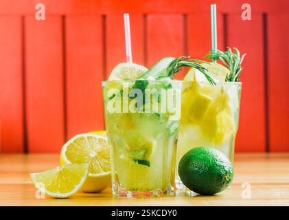 Cocktail rinfrescanti con agrumi ed erbe aromatiche su un tavolo di legno in un ambiente vivace Foto Stock