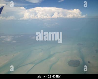 Foto aerea di acque turchesi poco profonde con macchie verdi scure. L'acqua bassa rivela forme vorticose delle barriere coralline. Le barriere coralline sono biodiversità Foto Stock