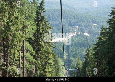 Giro in funivia sulla lussureggiante valle verde con stazione sciistica annidata tra le montagne. Splendide viste panoramiche del paesaggio circostante. Evoca s Foto Stock