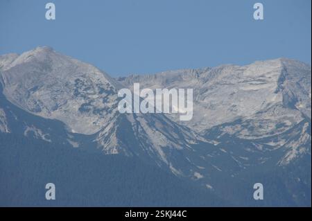 Catena montuosa, BULGARIA. Le cime innevate si innalzano sopra una valle, IN BULGARIA. Terreno accidentato. Un simbolo di forza e resilienza. Un ricordo del powe Foto Stock