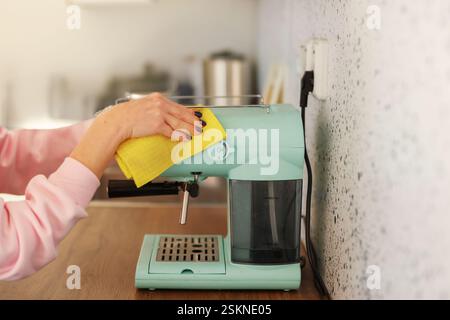 una ragazza con una giacca rosa lava la macchina del caffè blu Foto Stock