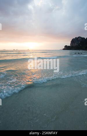 Un tranquillo tramonto a Railay Beach, Thailandia, con dolci onde che si infrangono sulla spiaggia sabbiosa. Foto Stock